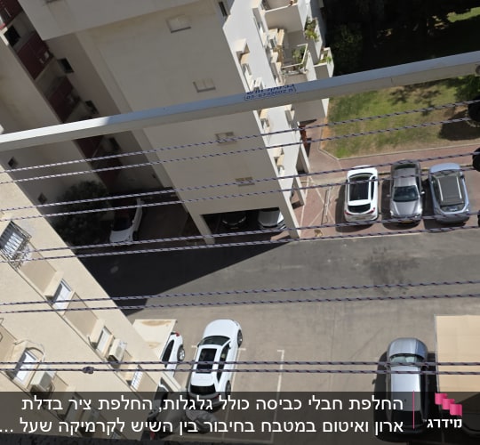 מתקן כביסה עם חבלים על רקע בניין וחניה